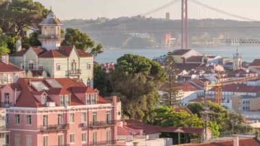 Lizbon, Tagus Nehri ve Köprüsü 'ndeki turuncu çatılar veya Portekiz' in yukarısından 25 Nisan Ponte de Abril hava zaman çizelgesi. Gün batımında Miradouro da Graca 'dan panoramik manzara