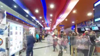 Aydınlatılmış İmax Sineması salonunda bir alışveriş merkezinin zaman atlaması içinde yürümek. Bilet gişeleri ve kafeler. Film başlamadan önce insanlar gidip geliyor..