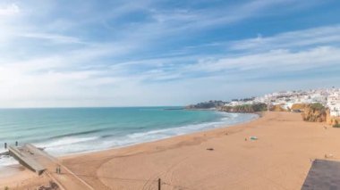 Panorama Albufeira Timelapse şehrinde geniş kumlu sahil ve Atlantik okyanusunu gösteriyor. Uçurumun tepesindeki beyaz evler. Yukarıdan hava görüntüsü. Mavi gökyüzündeki bulutlar. Algarve, Portekiz
