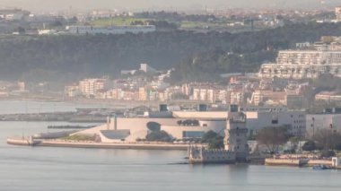 Portekiz 'in Lizbon şehrinin en ünlü simgelerinden biri olan Belem Kulesi zaman çizelgesinin hava görüntüsü. Gün batımından önce sisli hava. Rıhtımda yürüyen insanlar ve arka planda binalar