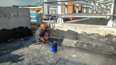 Roofer installing roofing felt with heating and melting of bitumen roll by torch on flame during roof repair timelapse. Construction process of roof covering and protection