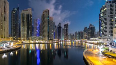 Dubai Marina Kanalı, modern kuleleri ve yatları olan liman kenti Dubai 'deki köprüden gece gündüz geçiş zamanı olan Birleşik Arap Emirlikleri' ne yansıyor. Güneş doğmadan önce etraftaki gökdelenler