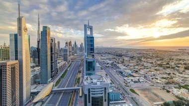 Dubai gökdelenleri, gün batımı akşam vakti. Dubai metro istasyonu ve Şeyh Zayed Yolu 'ndaki trafik. Kule çatısından gökyüzü görüntüsü. Güzel renkli bulutlu gökyüzü