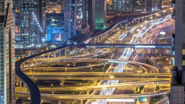 Aerial top view of highway junction with traffic timelapse in Dubai, UAE at night. Famous Sheikh Zayed road in Dubai downtown. Transportation and driving concept view from rooftop. clipart