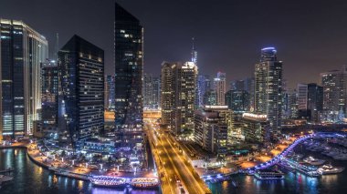 Su kanalı ve Dubai Marina manzarası, gece timelapse güvertede. Konut kuleleri aydınlatma ve aydınlatma ile. Yat ve tekne trafiği olan gökdelenler yüzen