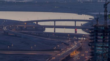 Güneş doğmadan önce Dubai şehir gece gün geçiş timelapse için meşgul bir kavşak trafik. Arka plan üzerinde Creek su ile yukarıdan üstten görünüm