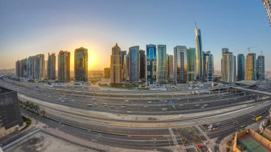 Jumeirah göl kulelerinin gökdelenleri gün doğumunda Şeyh zayed yolunda ve metro hattında trafik varken. Dubai marinasından çatı manzarası
