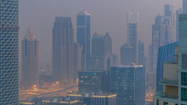 Sisli sabah gün geçiş timelapse gecesine Dubai şehir merkezinde. Şehir gökdelenler fütüristik görünümünü Şeyh zayed yolu üzerinde sis kaplı. Çatı güneş doğmadan önce havadan görünümden. Dubai, Birleşik Arap Emirlikleri