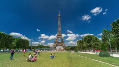 Paris 'teki Champs de Mars' taki Eyfel Kulesi. Zaman atlaması, Fransa. Yazın mavi bulutlu gökyüzü Yeşil çimlerle ve insanlar etrafta yürüyüp rahatlıyorlar