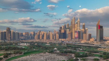 Dubai Marina skyscrapers and golf course morning timelapse, Dubai, United Arab Emirates. Aerial view from Greens district. Green lawn and cloudy sky clipart