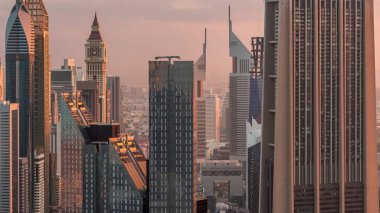 Dubai Uluslararası Finans Merkezi semt ışıklı modern gökdelenler sabah timelapse ile. Sıcak ışık ile gün doğumu sırasında sokaklarda trafik ile Downtown havadan görünümü