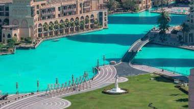 İnsan yapımı göl üzerindeki köprünün havadan yakından görünümü ve Dubai şehir merkezinde el anıtı sabah timelapse ile parkta yürüyen bazı insanlar, Birleşik Arap Emirlikleri.