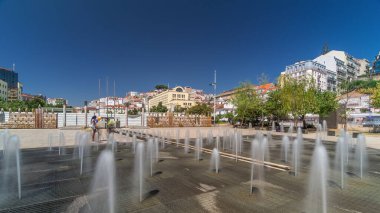 Lisbon şehir merkezinde Martim Moniz Meydanı 'ndaki çeşme. Tepelerde mavi gökyüzü olan tarihi binalar