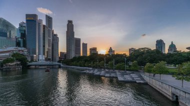 Singapore skyscrapers skyline with white Anderson Bridge and a few towers of financial district near esplanade park park day to night transition timelapse. Some green foliage on both sides. clipart