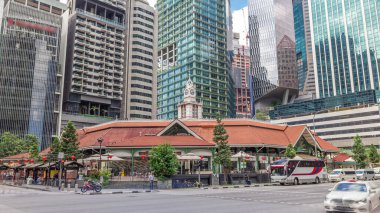Yüksek gökdelenleri olan Telok ayer pazarı arka planda zaman ayarlı hiperhızlandırılmış. Önündeki Raffles Quay ve Boon Tat caddelerinin kesiştiği yerde trafik vardı.