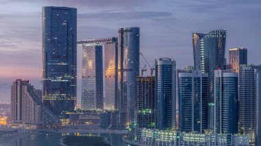 Abu Dabi 'deki Al Reem' deki gökdelenler gün doğumunda gökdelenler. Al Reem Adası 'ndan sabah sisli bir şehir manzarası. Güneş cam yüzeyine yansıyor