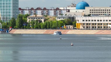 Astana, Kazakistan. Astana 'da Ishim nehrinde hareketli bir eğlence teknesi var. Yazın mavi gökyüzü ve bulutlarla
