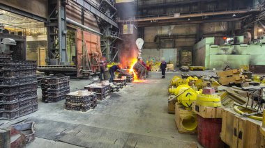The liquid metal is poured into molds at the metallurgical plant timelapse hyperlapse. Worker controlling metal melting in furnaces. Factory workshop with steelmaking furnace