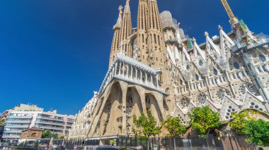 Sagrada Familia: İspanya 'nın Barcelona kentindeki Iconic Roma Katolik Kilisesi' nden Timelapse Hyperlapse. Sonbaharın Zarif Yeşilliği ve Mavi Bulutlu Gökyüzünün Altında Açılan Mimari Mucizeye Şahit Ol.