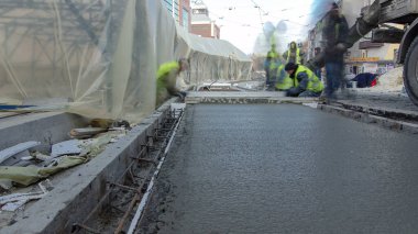 Çelik takviyesi yaptıktan sonra beton karıştırıcı zaman aşımına uğrayarak yolu hızlandırmak için hazır beton dökülüyor. Çadırla kaplı yeni raylar. Tramvay raylarının yeniden inşası