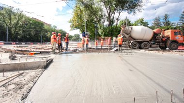 Tramvay rayları onarılan ve bakım süreleri yüksek olan yol inşaatı. Metal bir şebekeye taze beton dökülüyor. Kavşağın ortası..