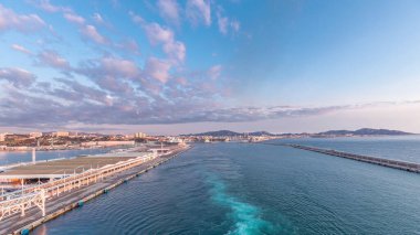 Gün batımında açık denizde yelken açan gemiden dalgalı ve limanlı deniz manzarası. Marsilya kıyısı, Fransa