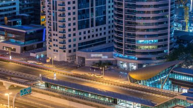 Dubai Yat Limanı gökdelenler ve tramvay istasyonu hava üstten görünüm güneş doğmadan önce Jlt gelen Dubai gece gün timelapse, Birleşik Arap Emirlikleri için. Işıklı modern kuleleri ve Şeyh zayed yolu üzerinde trafik.