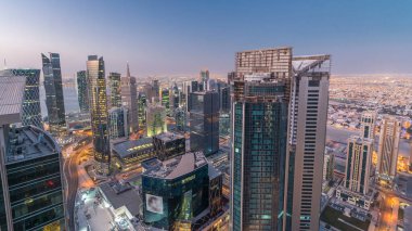 Batı Körfezi bölgesinin ufuk çizgisi Doha 'da gece gündüz geçiş zamanı, Katar. Aydınlatılmış modern gökdelenler. Sabah güneş doğmadan önce çatıdan gökyüzü manzarası.