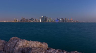 Arap şehri Doha 'nın ufuk çizgisi gece gündüz Katar' daki geçiş zamanı, gün doğumundan hemen önce aydınlık gökdelenlerle yakalandı. Corniche Gezinti Alanından Görünüm