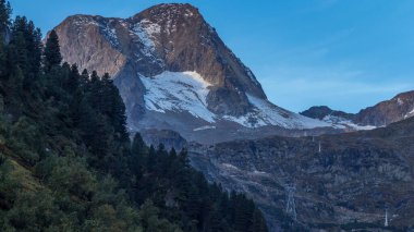 Alpler 'de güneş doğarken sabah görüşü etkileyici bir ışık ve bulutla. Tyrol, Avusturya. Ön planda çimenler ve kayalar aydınlandı. Biraz karlı Rocky dağları. Dağlardaki gölgeler