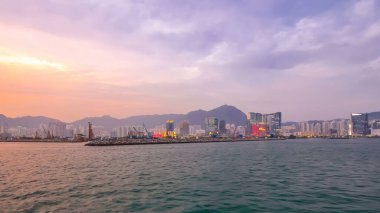 Star Ferry 'den Victoria Limanı' na diğer gemiler de günbatımında arka plan olarak Hong Kong 'un ufuk çizgisi ile birlikte seyir halinde.