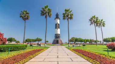 Miraflores Parkı 'ndaki deniz feneri manzaralı anıt zaman atlaması. Çiçekli ve palmiyeli yeşil çimenler. Güneşli bir günde sahil şeridi parkı. Lima, Peru