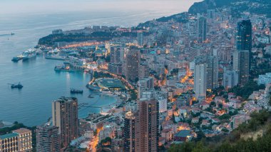 Monako 'nun büyük Corniche yolundan gece geçiş zamanına, Monako Fransa' ya giden hava manzarası. Akşam aydınlatması. Limanın suyundaki yansımalar