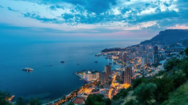 Monako 'nun havadan panoramik manzarası. Büyük Corniche yolundan geceye geçiş zamanı, Monako France. Akşam aydınlatması. Limanın suyundaki yansımalar