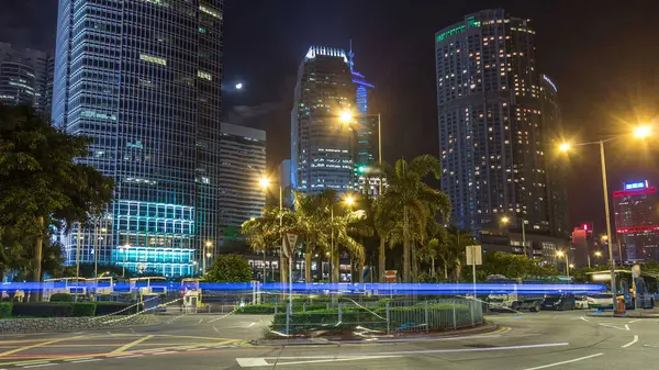 Modern şehir trafiğinin gece aşırı hızlanması caddenin karşısındaki otobüs durağı yakınında gökdelenlerle birlikte. Zaman aşımı. Hong Kong.