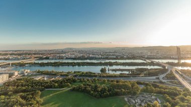 Aerial panoramic view of Vienna city with highway intersection, historic buildings and a riverside promenade timelapse in Austria. Evening skyline before sunset from Danube Tower viewpoint clipart