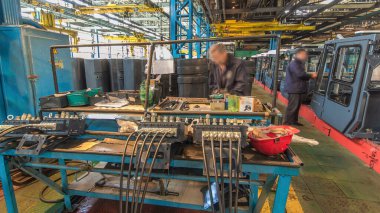 Konveyör montajı, traktörün gövdesini büyük endüstriyel fabrika zaman diliminde sahneleyecek. Kabin montajı, kurulum parçaları özel bir masada.