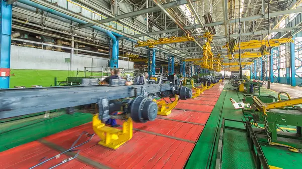 Konveyör montajı, traktörün gövdesini büyük endüstriyel fabrika zaman diliminde sahneleyecek. Çerçeve montajı, montaj parçaları. Arkaplanda çalışma bankları