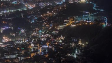 Georgia 'nın Tiflis şehrinde ahşap oymalı balkonları olan renkli geleneksel evler. Aydınlatılmış binalar, teleferik ve yol trafiği