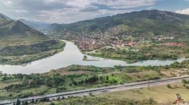 Kura ya da Mtkvari ve Aragvi nehirlerinin tek bir zaman diliminde birleşmesinin havadan görüntüsü. Gürcistan 'ın eski başkenti - Mtskheta doğru. Şehrin güzel manzarası, Georgia. Bulutlar geçip gidiyor