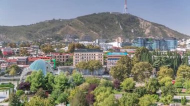 Yukarıdan Rike Park 'a. Tiflis 'in eski bir kasabasındaki modern şehir parkı. Şehirdeki dinlenme bölgesinde yeşil ağaçlar ve çimenler. Huzur Köprüsü ve arka plandaki evler. Georgia