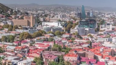 Tiflis 'teki cam otel kulesinin bulunduğu şehir manzarası zaman çizelgesi, Georgia gökdelenleri, Rustaveli Bulvarı' nda. Saati olan tarihi bir bina. Bakış açısından bak