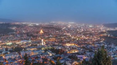 Alacakaranlıkta Tiflis şehri, Gürcistan 'dan gece geçiş zamanı. Şehir merkezinin ve Tiflis 'teki Kura Nehri' nin üst manzarası. Gün batımından sonra Gürcistan başkentinin havadan görünüşü