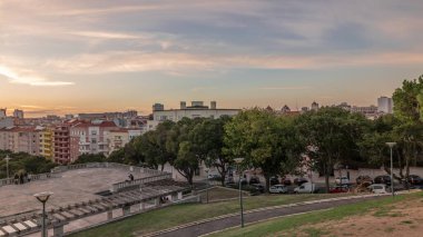 Panorama Alameda Dom Afonso Henriques 'deki çimlerin üzerinde gün batımını renkli binalar ve Aydınlık Çeşme hava saatleriyle gösteriyor. Lizbon, Portekiz 'de akşam gökyüzü ile yukarıdan görünüm