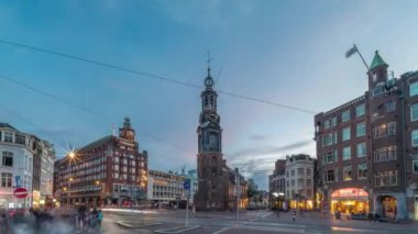 Munttoren Kulesi ve çiçek pazarı. Amsterdam şehir merkezinin panoramik günden geceye geçiş dönemi aşırı hızlanması tramvaylı sokak trafiği. Gün batımından sonra şehir manzarası. Hollanda