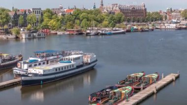 Oosterdok Limanı 'ndaki iskelede botları olan Amsterdam gökyüzü manzarası. Amsterdam Centraal İstasyonu ve Scheepvaarthuis yakınlarındaki geleneksel Hollanda mimarisi. Amsterdam, Hollanda