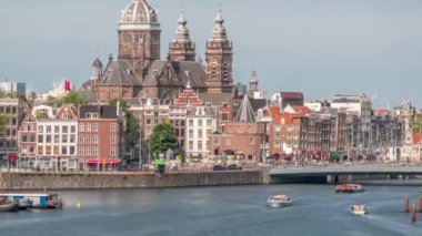 Merkez İstasyonu yakınlarındaki Amsterdam Eski Merkezi 'nde Aziz Nicholas Bazilikası ile birlikte havadan şehir manzarası. Tekne istasyonunda sahil şeridi boyunca yürüyen insanlar var. Amsterdam, Hollanda