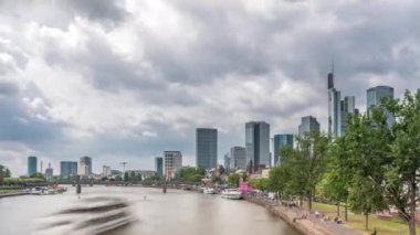 Almanya 'nın Frankfurt kentindeki ana nehir üzerindeki tarihi Eiserner Steg Demir Köprüsü' nün hızlandırılması. Gökdelenler ufuk çizgisi ve kıyı şeridi bulutlarla dolu bir gökyüzünün altında yansıyor.