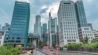 Frankfurts Innenstadt bölgesindeki cam gökdelenlere bakıyorum. Modern mimari gökyüzünde yağmurlu bulutları yansıtır. Yol ayrımında trafik vardı. Almanya.