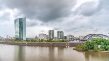 Frankfurt silueti, yansıtıcı çelik-cam cepheli modern ECB merkez gökdeleniyle, tren kemer köprüsü ve gökyüzündeki yağmurlu bulutlarla kaplıdır. Frankfurt am Main, Almanya